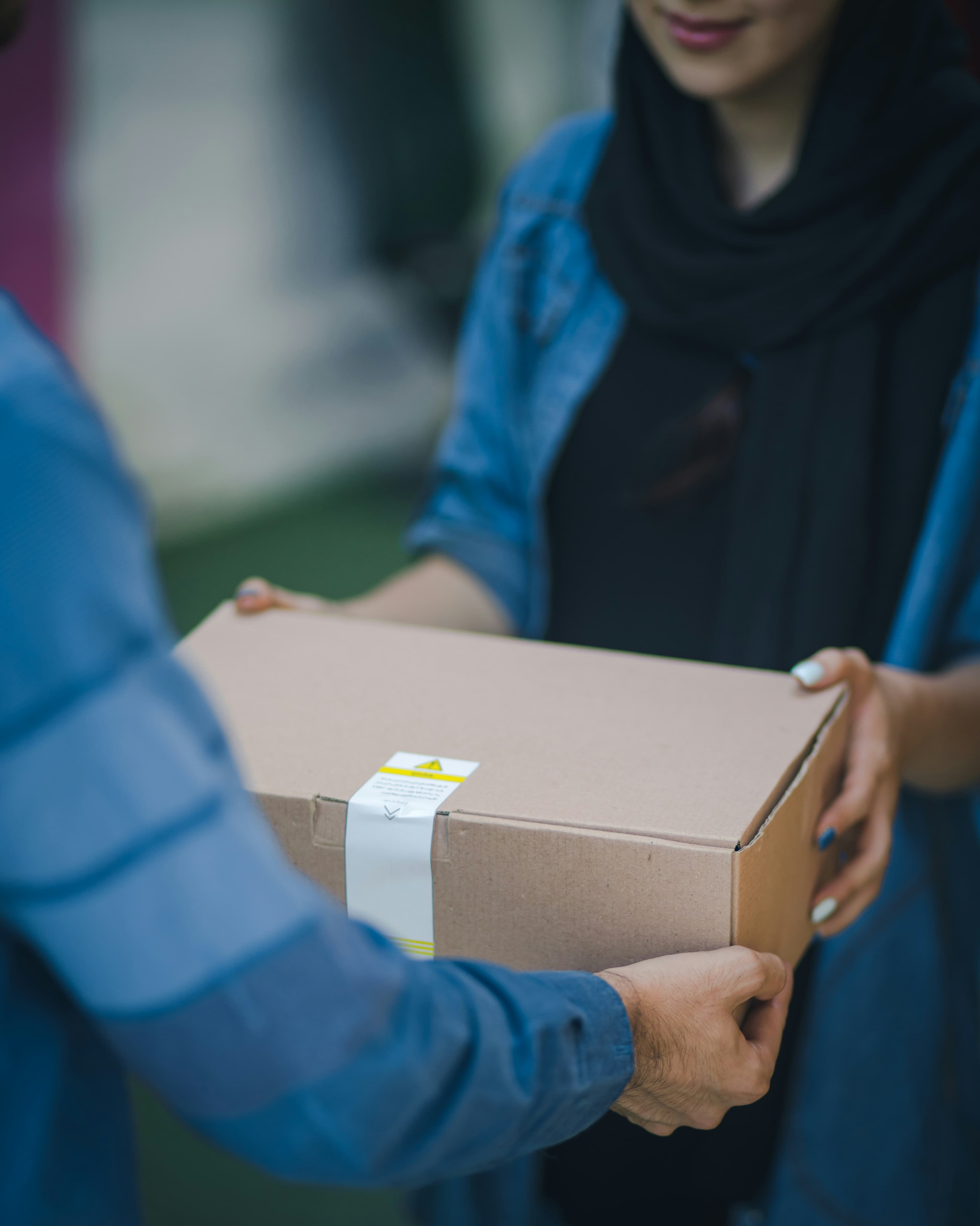 Consegna di un pacco di cartone fra due persone